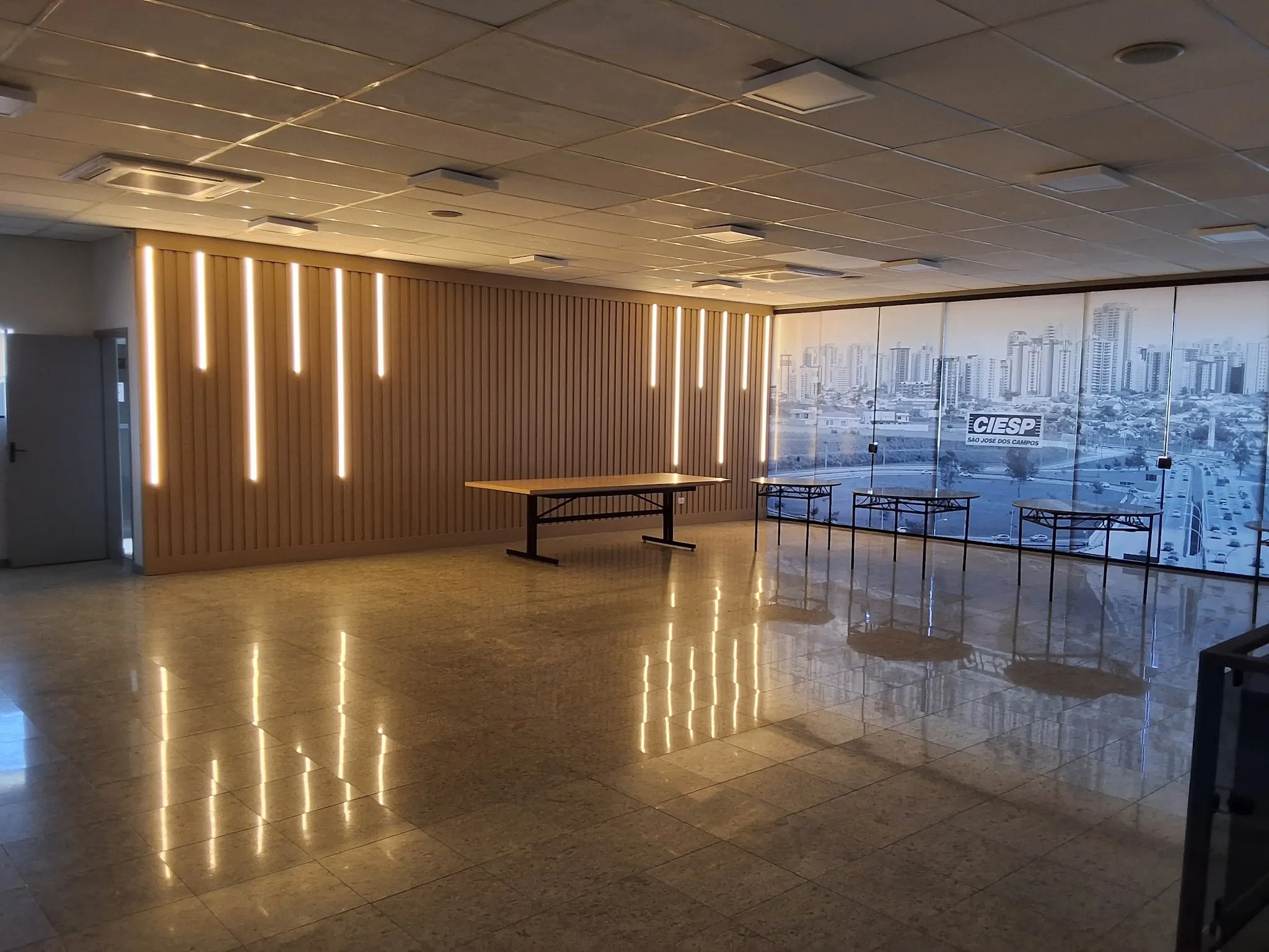 Salão corporativo com painel ripado de madeira e iluminação vertical embutida
